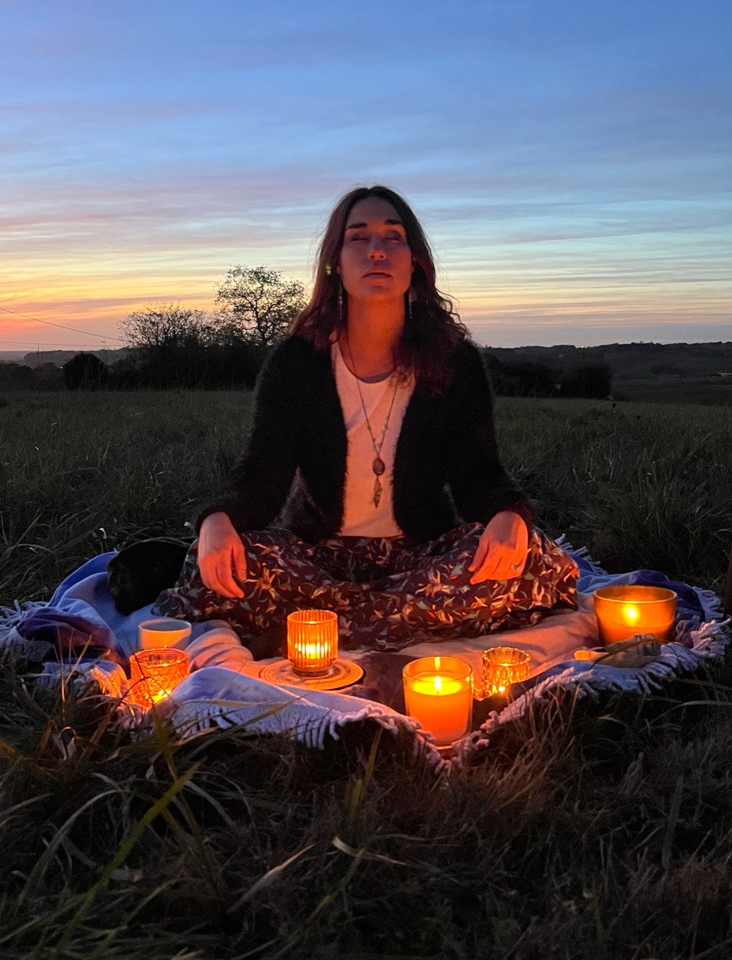 Jade assise en méditation au crépuscule, entourée de bougies