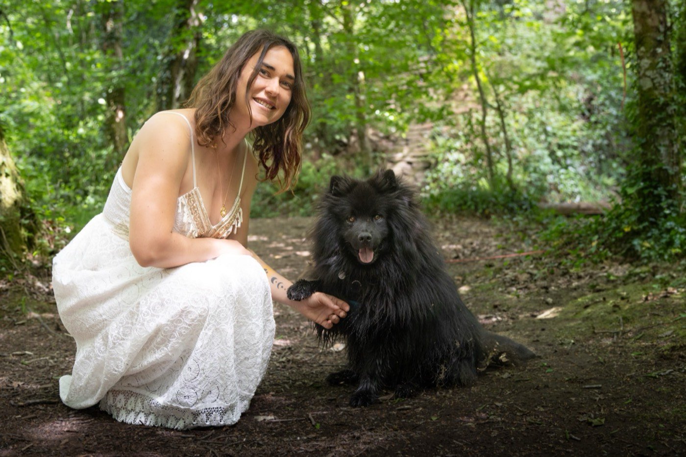 Jade souriante, accroupie en forêt aux côtés d'Alpha